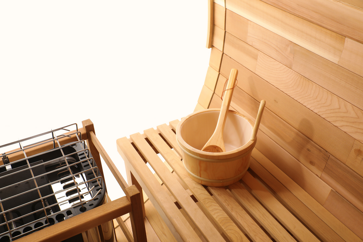 Wooden bucket and ladle on a cedar bench beside the heater inside the Blisspod Prague sauna