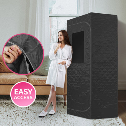 Portable steam sauna set up indoors with woman standing beside it
