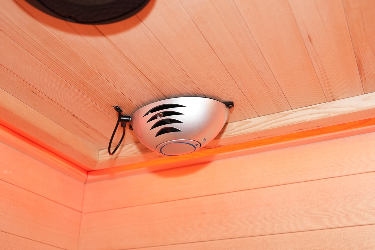 Close-up of a circular ceiling fixture and surrounding wood panels inside the Blisspod Venetian RED sauna
