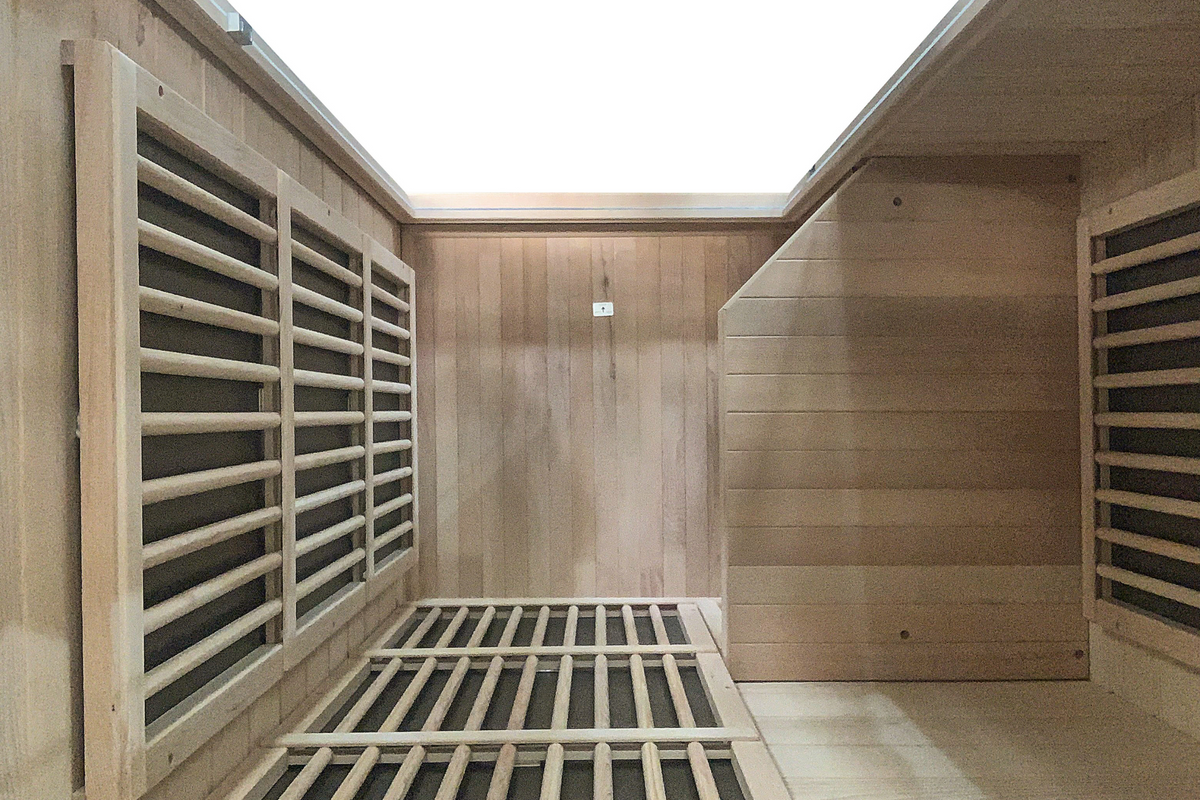 Interior of Blisspod Vienna 1-person far infrared sauna showing carbon heating panels, wooden heater guards and Canadian hemlock bench