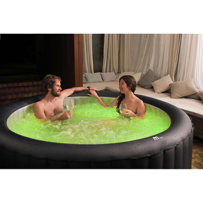 Two people relaxing in an MSpa AURORA hot tub with green LED lighting
