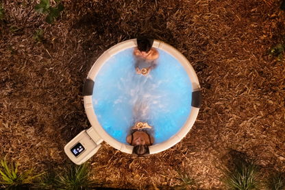Overhead nighttime view of people in the MSpa Denver hot tub with blue-lit water