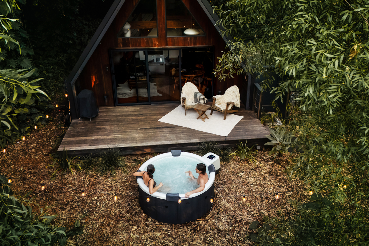 MSpa Denver hot tub in a garden beside a wooden seating area surrounded by greenery