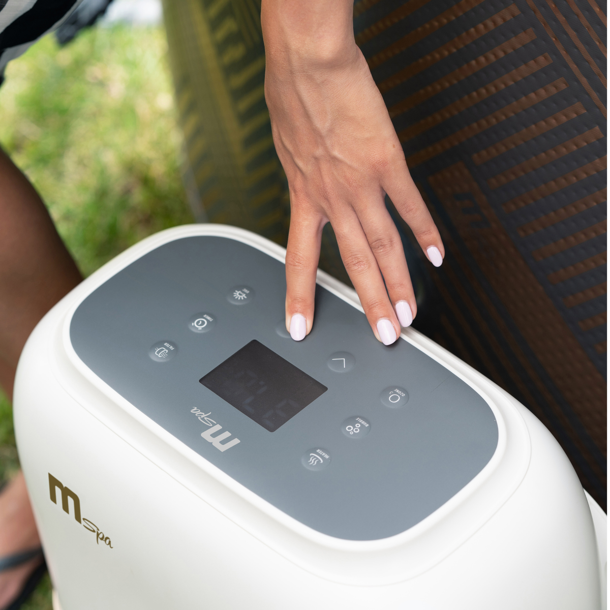 Hand adjusting the digital control panel of the MSpa MONO inflatable hot tub

