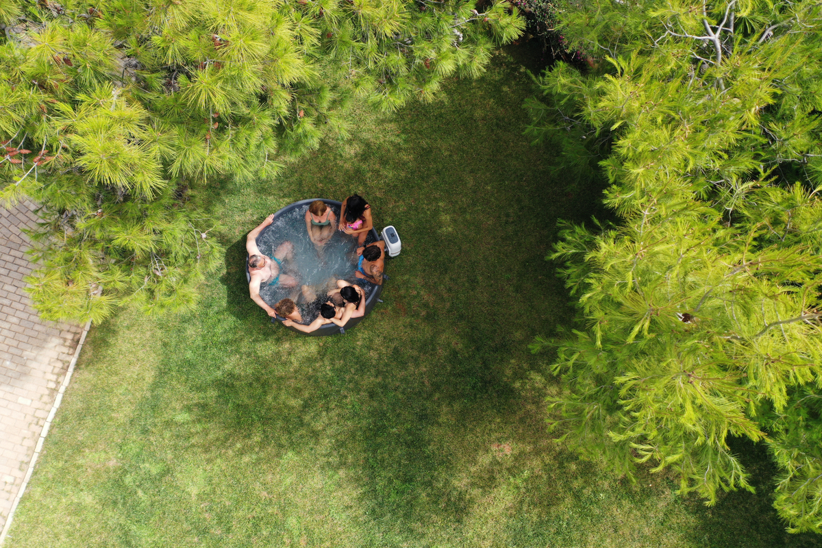 Overhead view of people enjoying the MSpa MONO round inflatable hot tub surrounded by greenery

