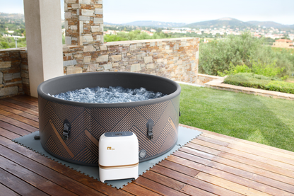 MSpa MONO inflatable hot tub with bubbling water on a wooden deck overlooking greenery
