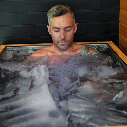 Man seated in the Revive Luxury cold plunge with floating ice visible around him.