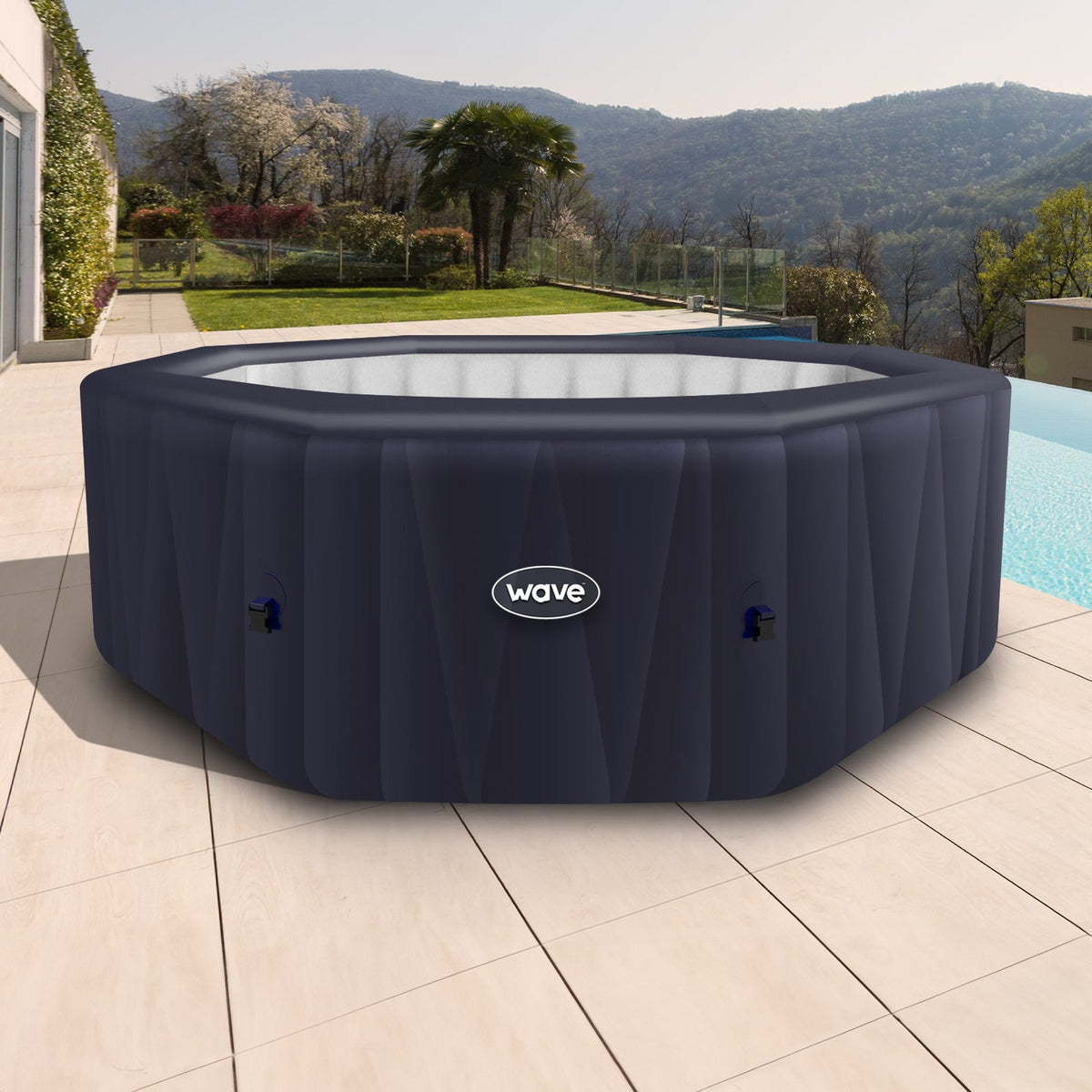 Navy Wave Aegean 6-person inflatable hot tub on a wooden deck beside a pool, with hills in the background